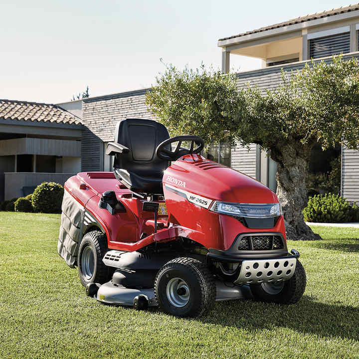 Driekwart vooraanzicht Honda zitmaaier in een tuin met huis op de achtergrond