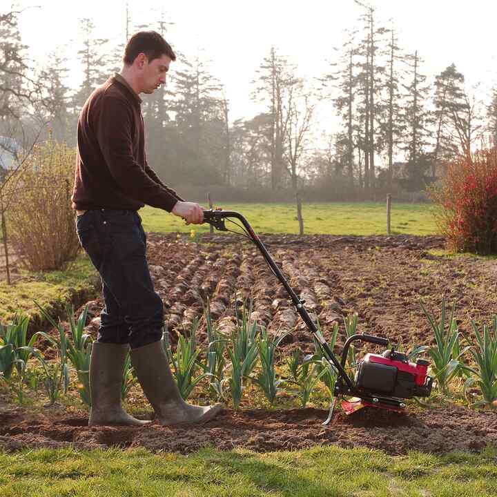 Honda microtuinfrees, rechter zijaanzicht, in gebruik op een veld.